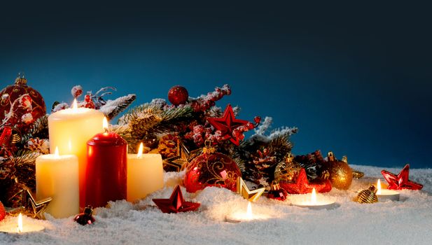Burning christmas candles with red and golden decorative stars , baubles , pine cones and green branches on snow