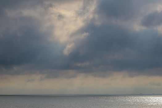 Beautiful sea panorama with empty horizon line and cloudy sky. Morning sky with dramatic clouds and Baltic sea in Latvia. Landscape of Baltic sea with shimmering water.