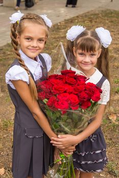 Two schoolgirls are holding a large bouquet of flowers in their hands