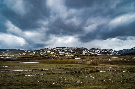 Wyoming countryside with mountain with snow and overcast cloudy sky.