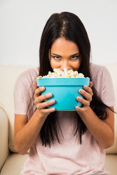 twenty something woman with her face in a bowl of popcorn