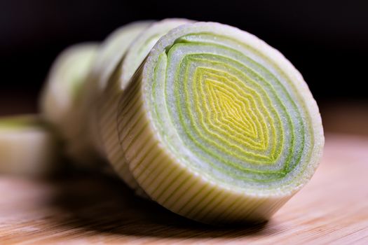 Closeup of fresh leek slices on a table with dark background