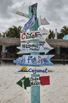 Sign with wooden arrows and blue, containing indications for cuba, florida, cozumel, ciuda de mexico and fish spa
