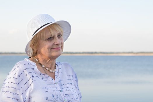 Happy smiling elederly retired lady woman rests in nature near lake river sea