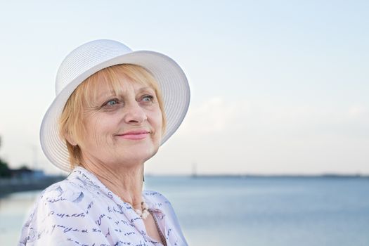 Happy smiling elederly retired lady woman rests in nature near lake river sea