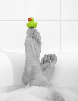 Men's feet in a bright white bathtub, selective focus on toes