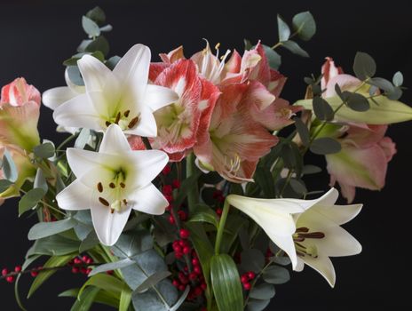 bouquet of flowers with white lily and red amaryllis and red bellies on a black background