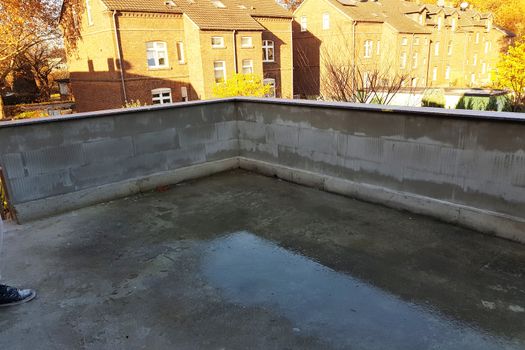 Renovated balcony with new concrete floor and brick balcony railing.