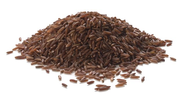 Close up photography of long grain red rice heap over white background. Packshot style 