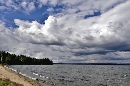 day lake in gray-white cloudy weather, South Ural, Uvildy, in the distance are seen the Ural mountains