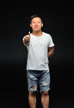 Portrait of a male Asian student of appearance on a black background that shows a thumbs up