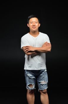 Portrait of a male Asian student of appearance on a black background that stands with folded hands