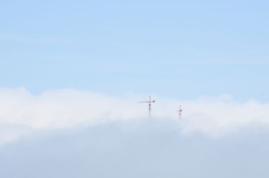 One frame with cranes in the blue sky above the clouds.There is large-scale construction of the city of Baku