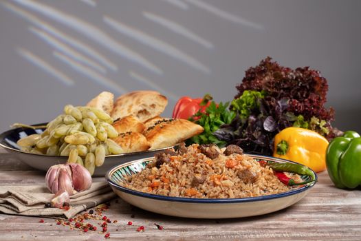 Asian traditional pilaw and vegetables on a wooden table