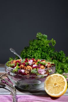 Plate with sald, lemon and greenery on a wooden table