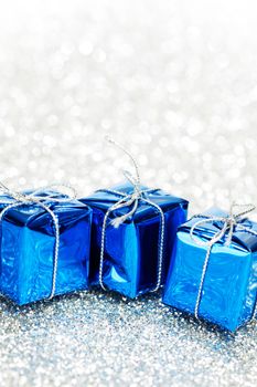 Small boxes with decorative holiday gifts on silver bokeh background