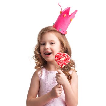 Beautiful little candy princess girl in crown holding big pink heart shaped lollipop and smiling