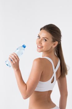 Beautiful woman in white sport lingerie with bottle of water over white