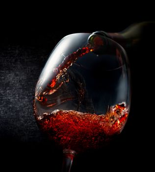 Wine pouring in wineglass on a black background