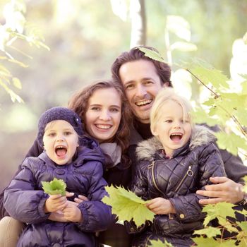 Happy family of parents and two children posing in autumn forest
