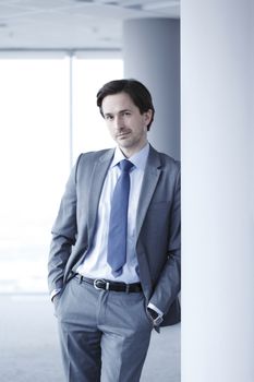 Portrait of handsome businessman standing near windows in office