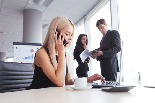 Young cute businesswoman talking on phone in office
