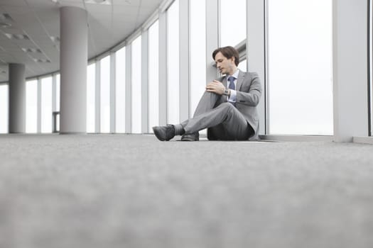 Businessman sitting on floor in office near window