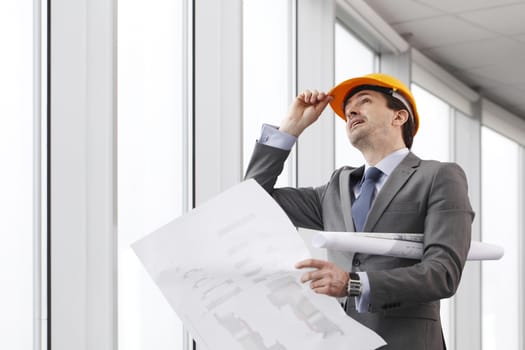 Architector in hardhat and business suit with construction plans