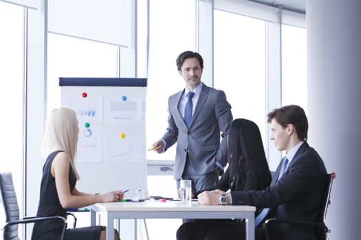Workers at business meeting looking at presentation of financial reports in modern office