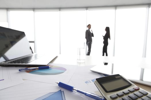 Financial reports, calculator and laptop on table in office