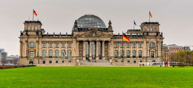 Reichstag building of German parliament in Berlin, German flags flying above the landmark of German capital