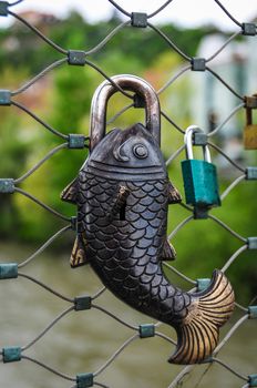 Fish lock on fence of bridge, a lock in the form of a fish on a bridge, eternal love and romance concept