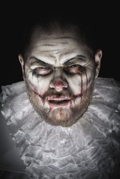 Portrait of a Scary Evil Clown.  Studio shot with horrible face art