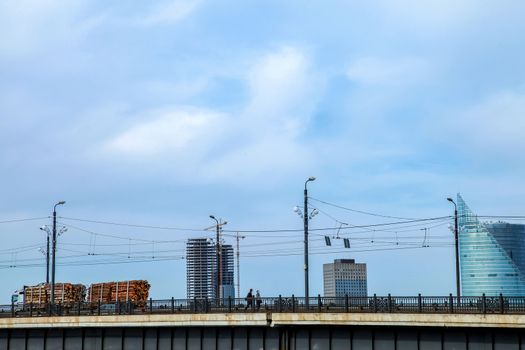 View of the Akmens bridge from the 11th November Embankment. Stone bridge on the blue sky background in Latvia. Bridge crossing vehicles and pedestrians. Stone bridge in Riga town.