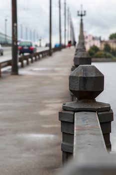 Fragment of Akmens bridge in Riga, Latvia. Stone bridge railings, blurred car traffic in the background. Stone bridge in Riga city.