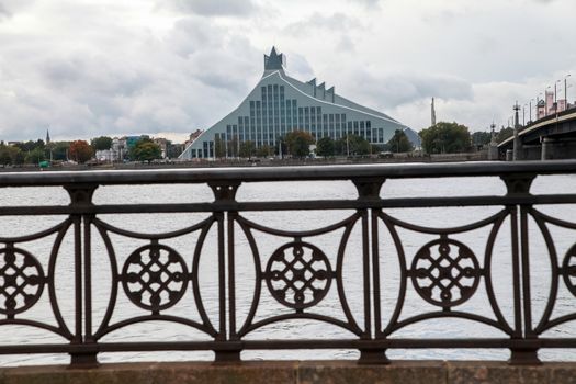 Latvian National Library. Cityscape from November 11 embankment with Latvian National Library in Riga. November 11 embankment bridge railings and National Library. National Library in center of Riga.