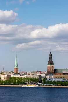 Riga, capital city of Latvia. View of St Peter's Church and St. Jacob's Cathedral. View of Old Riga with Daugava river in the foreground. City Riga with background of blue sky. View of Riga with ld buildings and historic architecture.