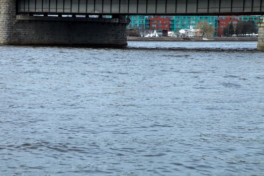 View of the Akmens bridge from the 11th November Embankment. Behind the Akmens bridge- residential buildings. On the front is the river Daugava. River under bridge in center of Riga.