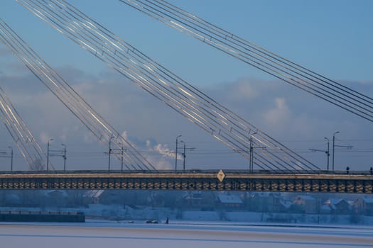 Fragment of Suspension bridge in winter. Vansu bridge over the frozen river Daugava in Riga. 
