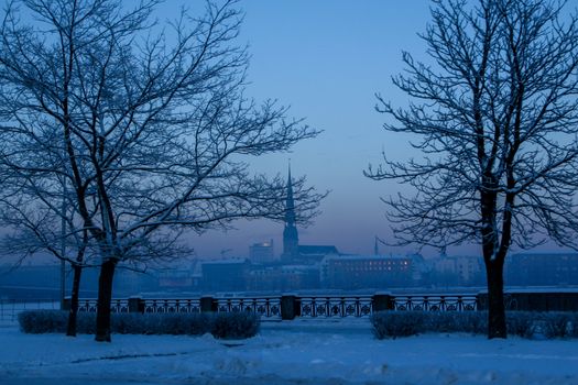 Riga view in winter; Riga, capital city of Latvia in winter time. View of St Peter's Church in winter. View of Old Riga with frozen river Daugava in the foreground. City Riga with background of blue sky. 