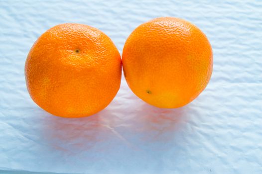 Two tangerines lie on a white background, a source of vitamins.