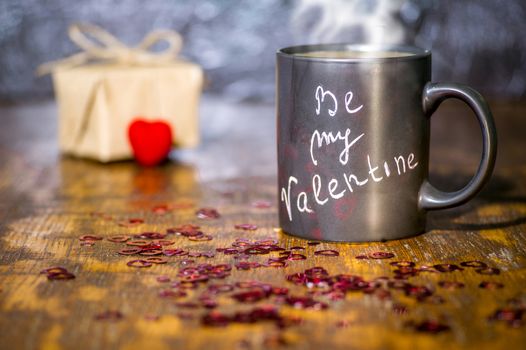 Valentine's day concept with black cup, chalk inscription on a mug and a red heart.