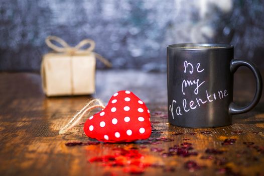 Valentine's day concept with black cup, chalk inscription on a mug and a red heart.