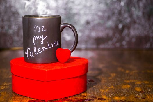 Valentine's day concept with black cup, chalk inscription on a mug and a red heart.