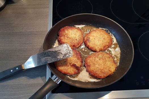 Potato pancakes in black frying pan, top view