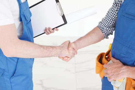 Two construction workers shaking hands, deal is finished concept