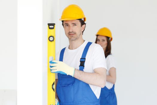 Team of workmen align wall using tools