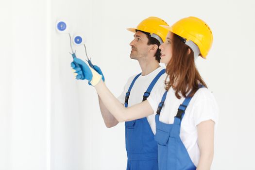 Two young workers in uniform painting the wall