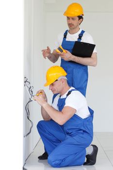 Two builders working with electricity indoors in new house