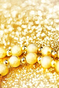 Golden decorative christmas beads on glitter background close-up